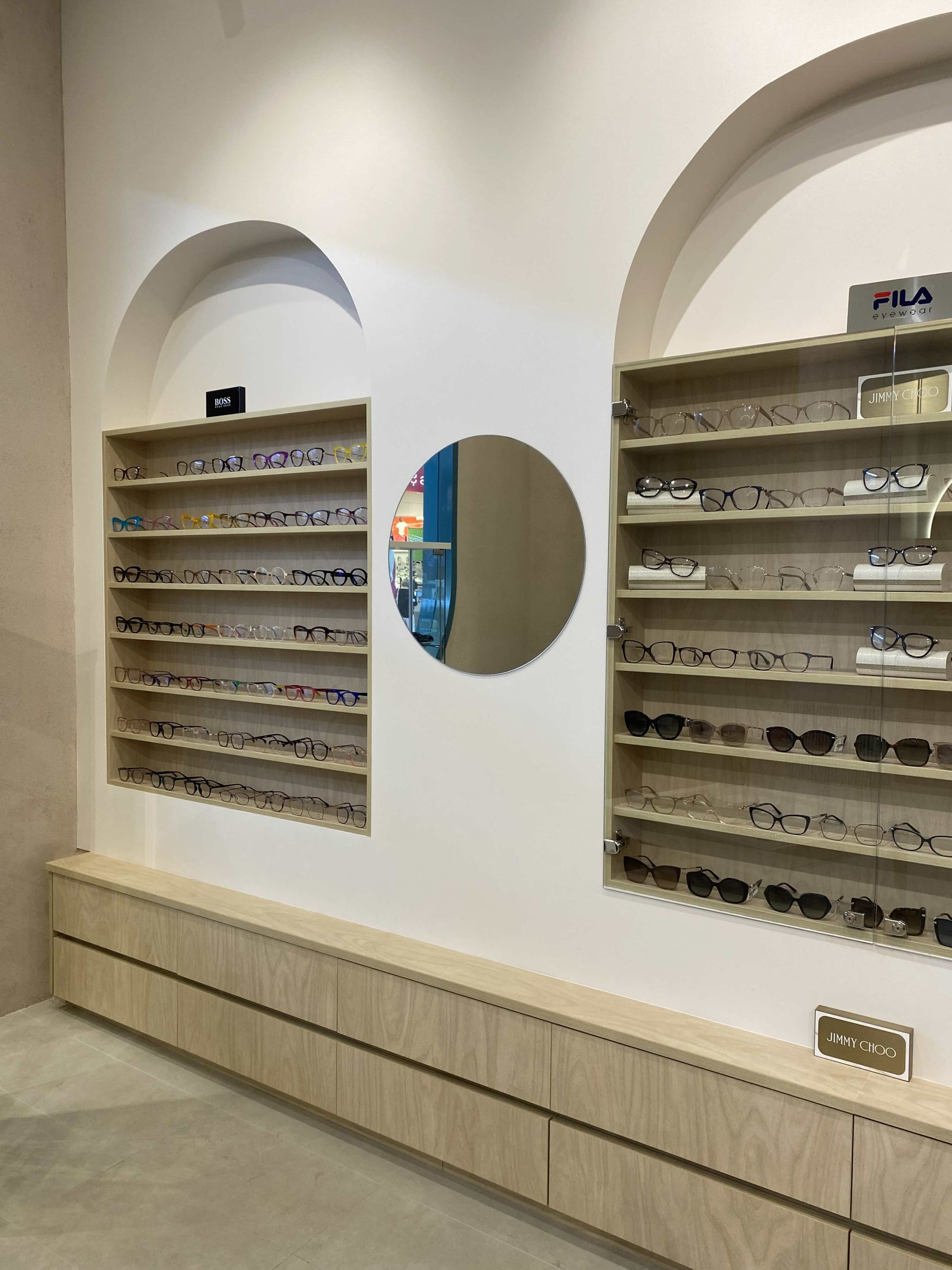 Optometrist retail fitout featuring custom eyewear display cabinetry, arched wall detailing and minimalist optical store interiors.